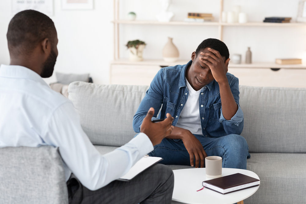 upset man sitting on white couch in treatment