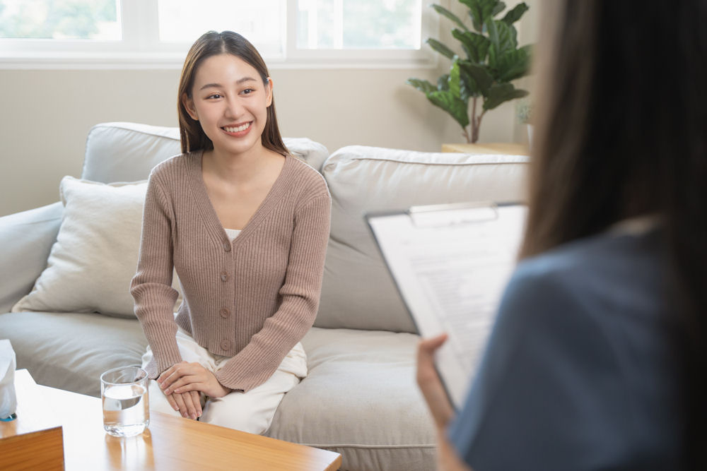 young woman sitting on couch and smiling during therapy session