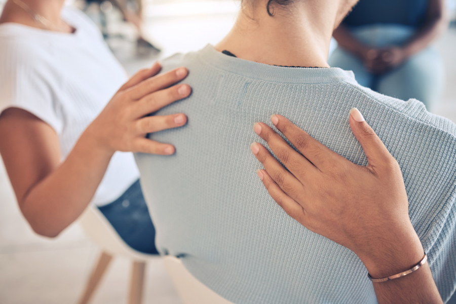 supportive hands on a group member's back during recovery
